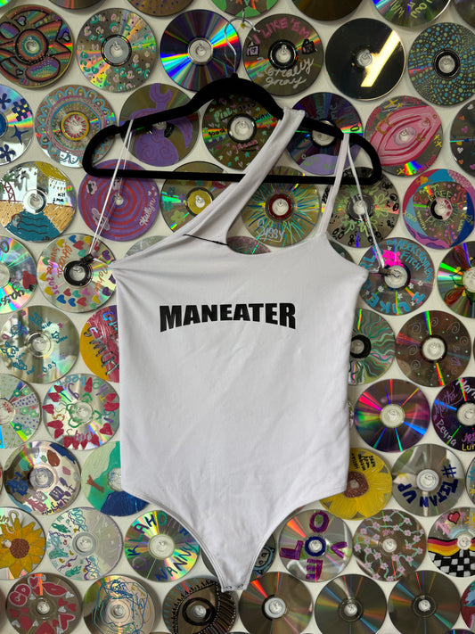 White t-shirt with 'MANEATER' printed on it displayed on a colorful background of CDs.