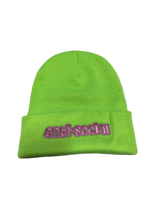 Green beanie with 'Anti-Social' text on a gray surface